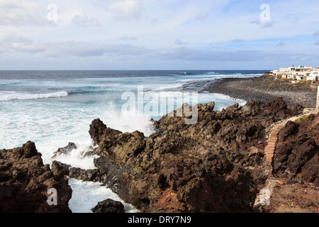 Raue See mit Wellen an Lavafelsen entlang der zerklüfteten Küste im kleinen Resort von El Golfo, Lanzarote, Kanarische Inseln, Spanien Stockfoto