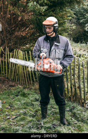 Porträt von professionellen Gärtner mit Kettensäge stehen im Garten. Stockfoto
