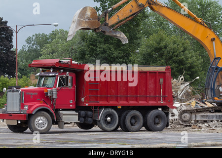 Baggerfahrer arbeiten auf Baustelle Bagger Abriss Gebäude in der Stadt Bagger lädt Schutt auf Müllwagen in Ohio USA Hi-res Stockfoto