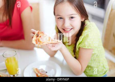 Porträt der niedliche kleine Mädchen beim Abendessen am Tisch saß und Pizza essen Stockfoto