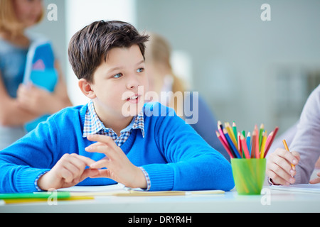 Porträt von niedlichen Schüler sitzen im Unterricht auf Grund seiner Klassenkameraden Stockfoto