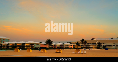 Sonnenaufgang am Strand von Fort Lauderdale mit Ferienwohnungen und Sonnenliegen am Strand. Stockfoto