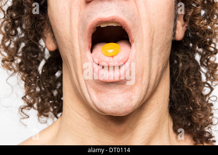 Schuss des mediterranen Menschen mit orange Pille in seine Zunge abgeschnitten Stockfoto