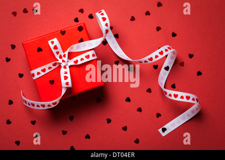Geschenkbox mit Schleife auf rotem Papierhintergrund. Valentines Day. Ansicht von oben Stockfoto
