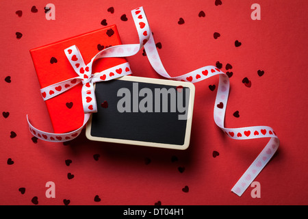 Geschenkbox mit gerahmten Tafel auf rotem Papierhintergrund. Valentines Day. Ansicht von oben Stockfoto