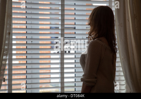 Silhouette der Trägerin einen Morgenmantel aus dem Fenster schauen. Über Schulter Rücken/Seitenansicht. Stockfoto