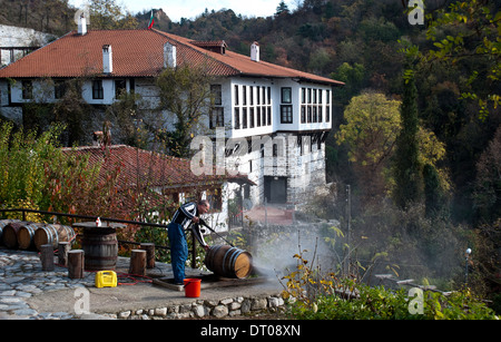 Mann ein Weinfass reinigen. Im Hintergrund, das Kordopoulov Haus aus dem 18. Jahrhundert (Bulgarien) Stockfoto