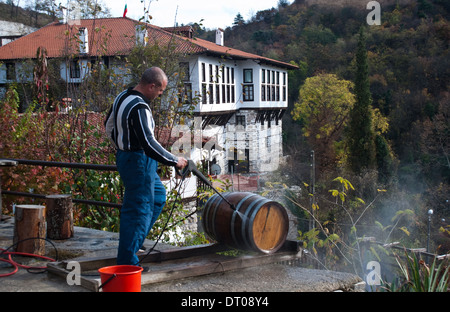 Mann ein Weinfass reinigen. Im Hintergrund, das Kordopoulov Haus aus dem 18. Jahrhundert (Bulgarien) Stockfoto