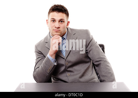 Studioportrait von nachdenklich Geschäftsmann am Tisch, mit Hand am Kinn, isoliert auf weißem Hintergrund Stockfoto