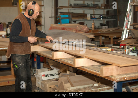 Zimmermann bei zwei großen Holzstücken mit Schraubzwinge in der Werkstatt. Stockfoto