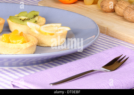 Verschiedene Mini Obstkuchen auf eine Keramikplatte mit Früchten im Hintergrund. Selektiven Fokus. Stockfoto