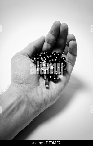 Mannes Hand mit hölzernen Rosenkranz mit katholischen Kreuz auf weißem Hintergrund Stockfoto