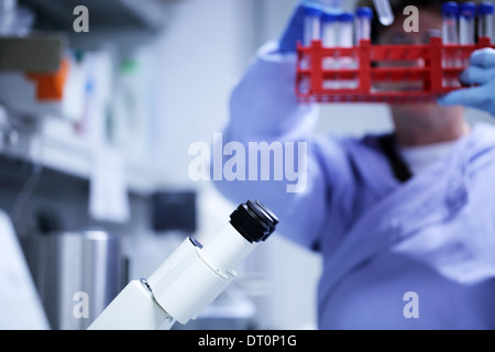 okuläre ein Mikroskop und ein Wissenschaftler mit blauen Kittel kaukasischen Frau arbeitet Stockfoto