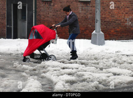 New York City, USA. 5. Februar 2014. Ein Fußgänger mit Kinderwagen überquert Schnee-beschichtete Straße in New York City in den Vereinigten Staaten, 5. Februar 2014. New Yorker Gouverneur Andrew Cuomo am Mittwoch erklärte einen Ausnahmezustand für alle New York State, effektive sofort ein Wintersturm weiterhin schweren Schnee, Eis und Eisregen für Gemeinden in den Bundesstaat und Downstate Regionen bringen. Bildnachweis: Gao Li/Xinhua/Alamy Live-Nachrichten Stockfoto