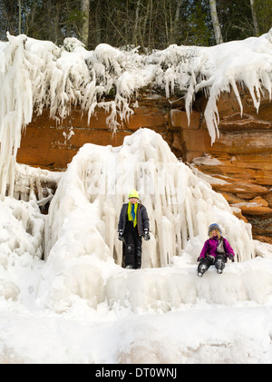 Ein Junge und ein Mädchen sitzen auf eine Eisbildung an den Apostel Insel Eishöhlen, Makwike Bay, nahe Bayfield, Wisconsin, auf einen kalten Februar Stockfoto