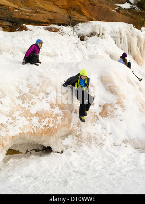 Eine Mädchen sitzt auf einer Eisbildung an den Apostel Insel Eishöhlen, Makwike Bay, nahe Bayfield, Wisconsin, an einem kalten Februartag. Stockfoto