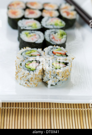 Closeup vertikale Foto frisch zubereiteten Kaliforniens und würzig Thunfisch Sushi rolls in weiße Platte und Chop-sticks Stockfoto