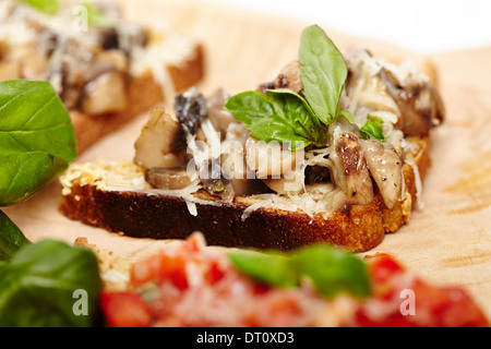 Nahaufnahme von frisch zubereiteten Pilz Bruschetta verziert mit Blättern Basilikum auf einem Holzbrett, selektiven Fokus Stockfoto