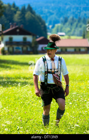 Mann im Kostüm flaniert durch Blumenwiese während traditionelle Bierfest in das Dorf von Klais in Bayern, Deutschland Stockfoto