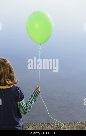 Seattle Washington USA Mädchen 9 hält grüner Ballon sitzen durch Wasser Stockfoto
