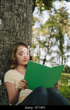 Seattle Washington USA neun Jahre alte Mädchen sitzen unter Baum Lesebuch Stockfoto