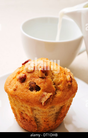 Nahaufnahme von einem Muffin in einen Teller und eine Tasse Milch auf einem gedeckten Tisch Stockfoto