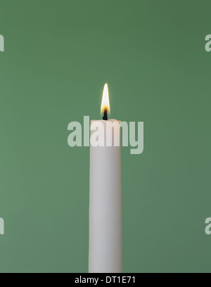 dünne weiße Wachskerze mit kleinen hellen Flamme Stockfoto