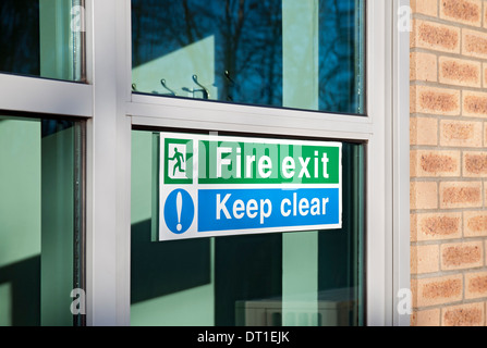 Nahaufnahme des Feuerwehrausgangs und klare Schilder an der Glastür halten England Großbritannien GB Großbritannien Stockfoto
