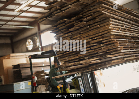 Ein Haufen von recycelten aufgearbeiteten Holz Holzplatten auf einem Gabelstapler LKW Reklamation in einem Holzlagerplatz verschoben wird Stockfoto