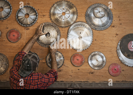 Ein neu gewonnenem Holz Workshop A Mann bis zu einer Speicher-Board für Kreissägeblätter, eine Klinge zu ersetzen Stockfoto