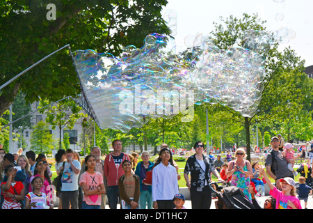 Familien genießen eine Demonstration der große Blase Kreationen mit einer großen Netz und Kabel Zauberstab auf zwei Pole Stockfoto