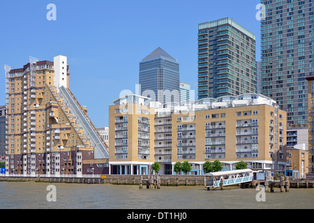 Modernes Apartmentgebäude am Wasser neben der Themse mit Canary Wharf Wahrzeichen Wolkenkratzer Büroblocks jenseits des blauen Himmels im Osten Londons Stockfoto