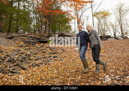 Ein paar Mann und Frau an einem Tag im Herbst zu Fuß durch gefallene Blätter Hand in Hand Stockfoto