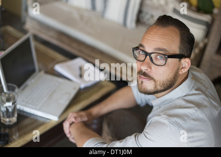 Ein Mann sitzt an einem Schreibtisch mit einem Laptop-Computer, die Führung eines kleinen Unternehmens Stockfoto