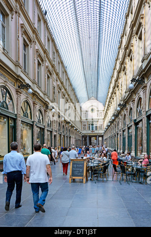 Menschen Flanieren entlang Galeries Royales Saint-Hubert Arcade/Einkaufszentrum mit Café-Tischen und Stühlen Stockfoto