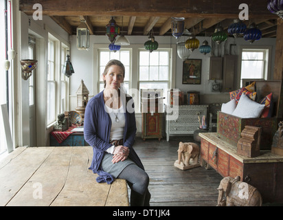 Eine Frau in einem Antiquitätengeschäft in einer Kleinstadt mit Objekten und Möbeln aus der Vergangenheit Stockfoto