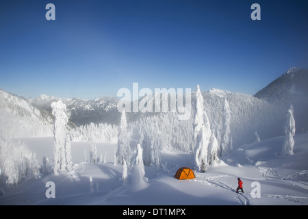 Michael Hanson Spaziergänge durch Tiefschnee auf seinem Campingplatz im Schnee bedeckt Cascade Mountains mit Blick auf Schnee See Stockfoto