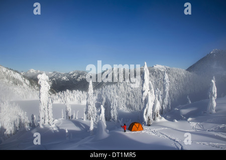 Michael Hanson Spaziergänge durch Tiefschnee auf seinem Campingplatz im Schnee bedeckt Cascade Mountains mit Blick auf Schnee See Stockfoto