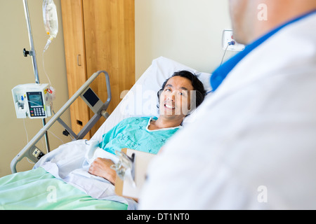 Glücklicher Patient Arzt am Krankenbett liegend betrachten Stockfoto