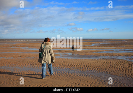 Frau zu Fuß mit ihrem Hund bei Holme-Next-the-Sea an der Küste von Norfolk. Stockfoto