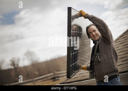 Ein Mann mit einem großen Solar-Panel über einen Hof Stockfoto