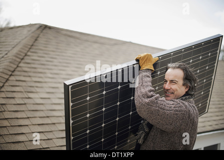 Ein Mann mit einem großen Solar-Panel über einen Hof Stockfoto