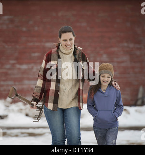 Eine Frau und ein junges Mädchen zu Fuß über einen verschneiten Hof Stockfoto