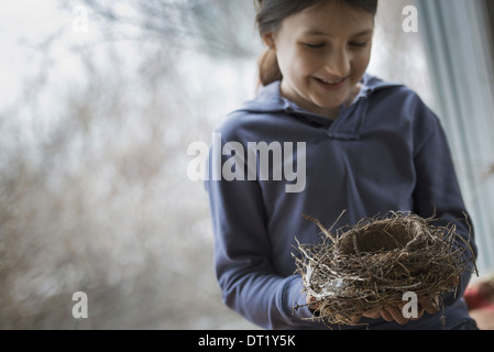 Ein Bio-Bauernhof im Winter in New York State USA A junges Mädchen hält ein Vogelnest, gewebt aus Zweigen und Blättern Stockfoto