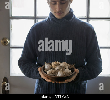 Ein Bio-Bauernhof im Winter in New York State USA A junger Mann hält einen Bogen von Knoblauch Zwiebeln Stockfoto