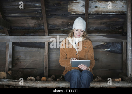 Ein Bio-Bauernhof im Bundesstaat New York im Winter A Frau sitzt in einem Nebengebäude mit einem digitalen tablet Stockfoto