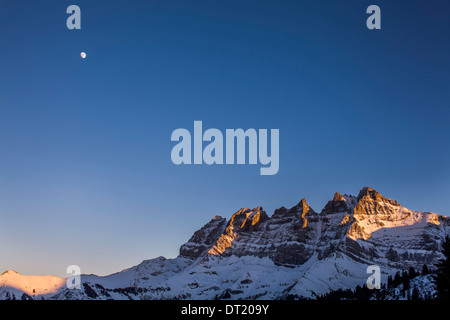 Der Mond erscheint über der Dents Du Midi als die Sonne untergeht. Stockfoto