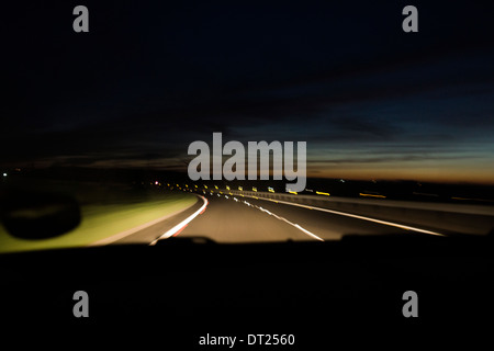 Auto Sonnenuntergang Nacht Scheinwerfer Lampen unterwegs Stockfoto