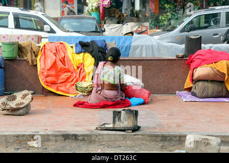 Neu-Delhi, Indien. 6. Februar 2014. Eine Frau sitzt an der Seite einer belebten Straße neben ihren provisorischen Hütte in Neu-Delhi, Indien, 6. Februar 2014. Bundespräsident Gauck ist derzeit auf einem sechstägigen Besuch in Indien. Foto: Wolfgang Kumm/Dpa/Alamy Live News Stockfoto