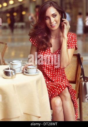 schöne Frau in einem Cafe sitzen und reden von mobile Stockfoto